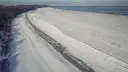 Zamarznięta plaża i Bałtyk, jakby czas się zatrzymał od kiedy powstało morze bałtyckie. W oddali widać statki.