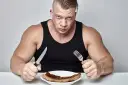Mięśniak z determinacją wpatruje się w stek, gotowy na wyzwanie, jak szybko przytyć.