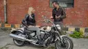Kobieta siedzi na motocyklu Yamaha Warrior 1700, mężczyzna obok opowiada o jego możliwościach.