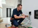 Elektryk podłączający kable domofonu i elektrozaczepu.