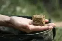 Gotowy do łowienia karpia metodą na karpia z gruntu. Wędkarz trzyma w dłoni podajnik z zanętą.