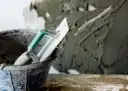 Łopata z zaprawą murarską w wiadrze, gotowa do pracy. Kluczowe są właściwe zaprawa murarska proporcje.