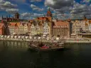 Żaglowiec na Motławie przed kolorowymi kamieniczkami w Gdańsku.