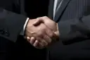 Uścisk dłoni dwóch mężczyzn w garniturach. Sfinalizowana darowizna mieszkania, symbol zaufania i porozumienia.