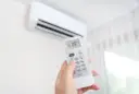 Dłoń trzymająca pilot do klimatyzacji, ustawiona na 19°C. Zastanawiasz się, ile kosztuje montaż klimatyzacji?