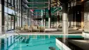 Basen z turkusową wodą i leżakami w nowoczesnym hotelowym spa.