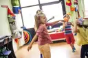 Dzieci tańczą i bawią się w sali pełnej zabawek. Czy to są gordonki? Radość i ruch!