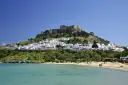Piękna pogoda na Rodos w maju. Białe domki Lindos i akropol na wzgórzu nad turkusowym morzem.