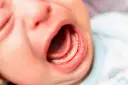 Usta niemowlaka z widocznym językiem i dziąsłami. Może to być związane z za krótkim wędzidełkiem u niemowlaka objawy.