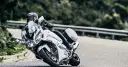 Motocyklista w kasku pochyla się na białym motocyklu Yamaha FJR 1300, pokonując zakręt. Dane techniczne tego modelu są imponujące.