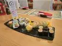 Talerz sushi z różnymi rolkami, w tym smażonymi i z łososiem, na czarnej desce.