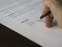Podpisanie umowy przedwstępnej sprzedaży mieszkania. Długopis kreśli podpis na dokumencie.