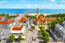 Widok z lotu ptaka na nadmorską miejscowość z plażą, molo i zabytkowymi budynkami.