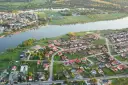 Widok z lotu ptaka na malownicze jezioro Pniewy otoczone zielenią i zabudowaniami.