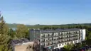 Widok na hotel Solina Resort & Spa z apartamentami i pokojami, otoczony zielenią, z jeziorem Solina w tle.