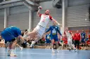 Gracz w białej koszulce z numerem 28 wyskakuje do rzutu podczas meczu polska Serbia piłka ręczna.
