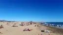 Tłum ludzi odpoczywa na słonecznej plaży. Woda jest spokojna, a niebo bezchmurne. Czy Gran Canaria jest bezpieczna? Tak, wygląda na to, że turyści czują się tu swobodnie.