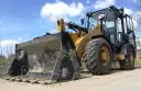 Żółta ładowarka stoi na piasku. Zastanawiasz się, ile zarabia operator koparki?