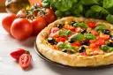 Pyszna pizza z pomidorami, oliwkami i kukurydzą, obok świeże pomidory i bazylia. Ile piec pizze?