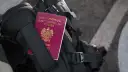 Polski paszport wpięty w czarny plecak podróżny.