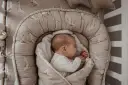 Śpiące dziecko w kokonie otulone miękkim otulaczem. Czy dziecko może spać w kokonie? Tak, jeśli jest bezpieczny i wygodny.