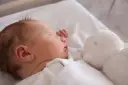 Słodki chłopczyk śpi obok białej przytulanki. Gratulacje z okazji narodzin syna!