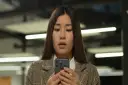 Zaskoczona kobieta patrzy na ekran telefonu komórkowego.