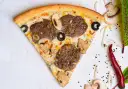 Kawałek pizzy z mięsem mielonym, pieczarkami i oliwkami na jasnym tle.