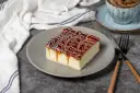 Pyszny kawałek ciasta Tres Leches z polewą karmelową i białą czekoladą. Idealny przepis na deser.