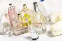 Mehrere Parfümflaschen, darunter Trussardi und Tommy Girl, auf weißem Handtuch mit weißen Tulpen.