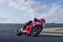Czerwony motocykl Honda CBR650R z kierowcą pochylonym na zakręcie toru wyścigowego.