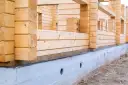 Budowa domu z bali drewnianych na betonowym fundamencie.