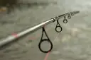 Idealny spinning na szczupaka z brzegu, z pomarańczową żyłką przechodzącą przez przelotki.