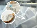 Łyżka białego proszku, prawdopodobnie krochmal, obok szklanki z wodą, wskazujące na białe koszule.
