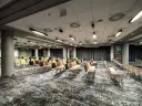 Sala konferencyjna w hotelu Mercure Wrocław, przygotowana na wydarzenie. Rzędy kolorowych krzeseł czekają na gości.