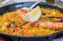 Paella z owocami morza i cytryną w czarnej patelni.
