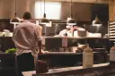 Kucharz w białej koszuli i fartuchu pracuje w kuchni restauracyjnej. To idealne miejsce, by napisać list motywacyjny kucharz.