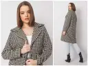 Elegancki płaszcz w klasyczną pepitkę, idealny na jesienne dni. Modelka prezentuje go z jeansami i botkami.
