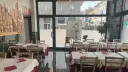 Restaurant interior with tables set for dining, featuring a mural of Milan's skyline.