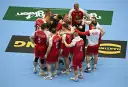 Drużyna piłkarzy ręcznych Polski w czerwonych strojach z białymi detalami, zjednoczona w kółku. To kluczowy moment przed meczem, być może decydującym o dalszych losach w mistrzostwach świata.