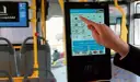 Ręka dotyka ekranu automatu biletowego w autobusie. Czy we Wrocławiu uczniowie jeżdżą za darmo? Tu kupisz bilet, sprawdzisz jego ważność i zapłacisz kartą.