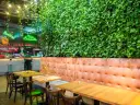 Wnętrze restauracji z zieloną ścianą i wygodnymi lożami. Idealne miejsce na odkrycie najlepszych restauracji w Krakowie - Ranking top 6.