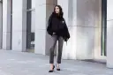 Kobieta w czarnej bluzie z kapturem i szarych jeansach. Luźny krój (loose fit) bluzy podkreśla swobodny styl.