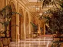 Elegancki korytarz z łukami i palmami, przypominający wnętrze najdroższego hotelu na świecie.