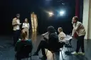 Aktorzy na próbie dyskutują o scenariuszu. Zastanawiają się, ile zarabia reżyser, gdy ich własne pensje są niepewne.