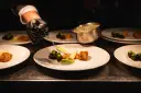 Szef kuchni precyzyjnie serwuje sos, dbając o zasady serwowania dań w stylu "fine dining" na dużych imprezach.
