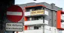 Baner "PRZEDAZ MIESZKAN" na nowoczesnym bloku. Czy to znak, dlaczego ceny mieszkań są tak wysokie?
