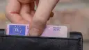 Dłoń wkłada do czarnego portfela polskie prawo jazdy. Widoczny numer blankietu prawa jazdy.