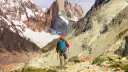 Turysta z plecakiem i kijkami trekkingowymi na tle ośnieżonych gór Patagonii.