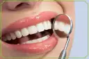 Biała dieta po wybielaniu zębów? Uśmiech jak z reklamy, lśniące zęby odbijają się w lusterku dentystycznym.